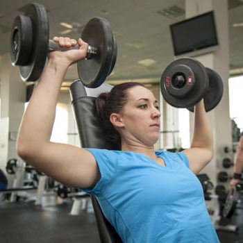 Client performing seated dumbbell press